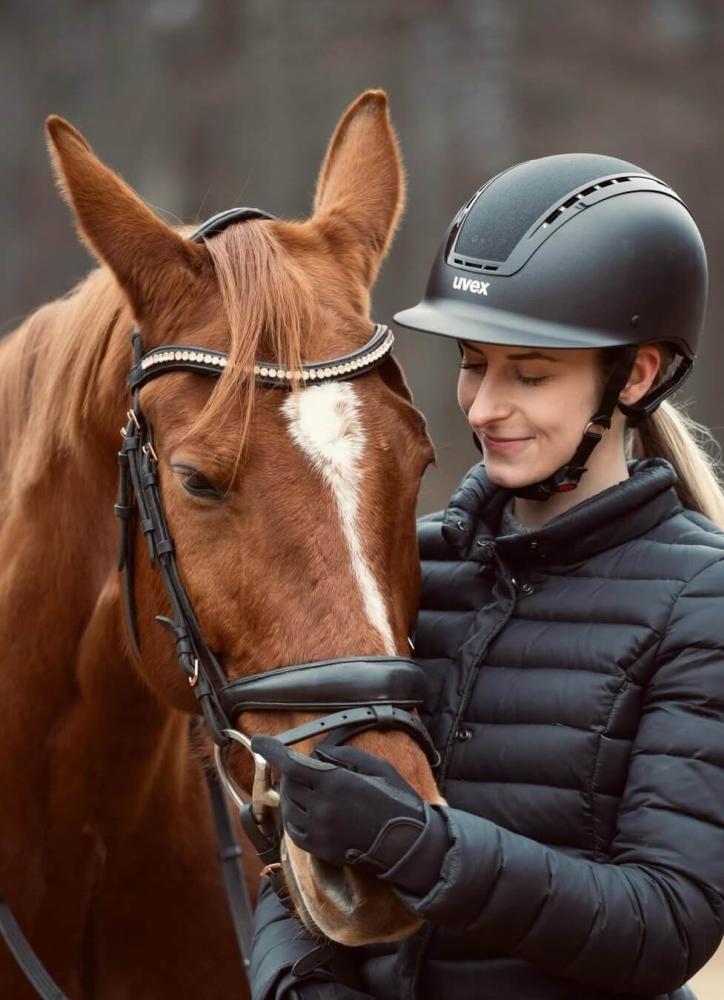 Rider standing beside a calm chestnut horse wearing a leather bridle, showing a quiet bonding moment Cavaletti Collection.